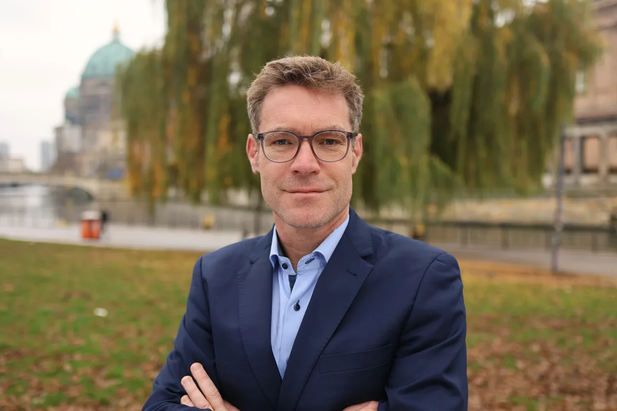 Constantin Zerger, Bereichsleiter Energie und Klimaschutz der Deutschen Umwelthilfe, im Porträt vor einer herbstlichen Uferkulisse.